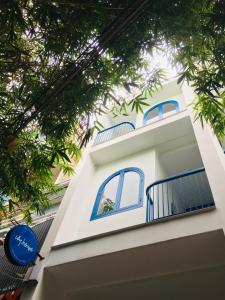 a white building with blue windows and trees at Ivy house in Hue