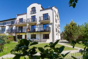 a white building with balconies and a yard at Porto in Karwia