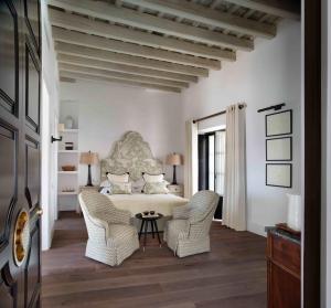 a bedroom with a bed with two chairs and a table at Hotel Plaza 18 - Grupo Califa in Vejer de la Frontera