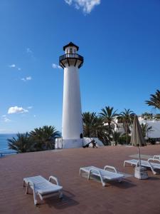 a lighthouse with lounge chairs in front of it at Charming Bellagio SUN CLUB in San Bartolomé