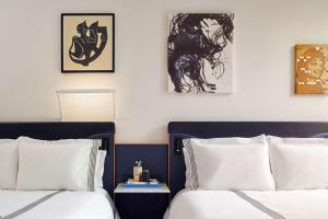 a hotel room with two beds and a painting on the wall at Thompson Seattle in Seattle