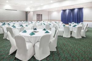 une salle de conférence avec des tables et des chaises blanches avec des serviettes bleues dans l'établissement Days Inn by Wyndham Kirksville, à Kirksville