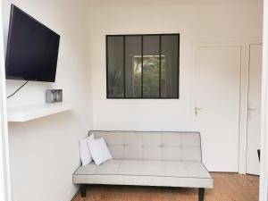 a living room with a white couch and a flat screen tv at Joli appartement à 2 pas de Paris in Bagnolet