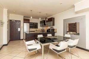 a kitchen with a black table and white chairs at ITC Icon Two bedroom Apartment with lovely balcony in Cape Town