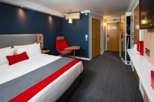a hotel room with a bed and a red chair at Holiday Inn Express Edinburgh - Leith Waterfront by IHG in Edinburgh