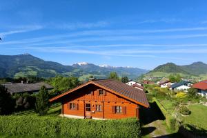 a wooden house on a hill with mountains in the background at Zechmann-Tauernblick in Gröbming