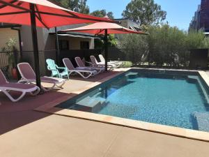 a small swimming pool with chairs and umbrellas at Adelphi Apartment 2- Poolside or Apartment 2A- King Studio in Echuca