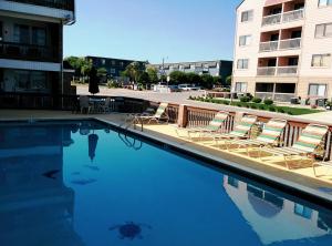 a swimming pool with lounge chairs and a building at El Dorado in Myrtle Beach