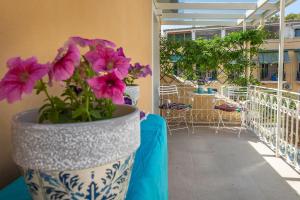 Corfu House of Art Suite - Anemomylos في Anemómylos: مزهرية مع الزهور الأرجوانية على طاولة