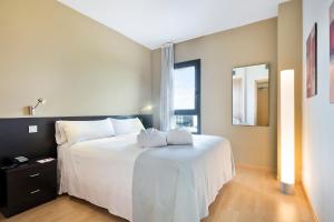 una camera da letto con un grande letto bianco e una finestra di Madrid Airport Suites, Affiliated by Meliá a Madrid