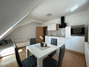 a kitchen and dining room with a white table and chairs at TM Apartments in Straß in Steiermark