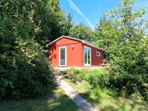 a red cabin in the middle of trees at Skovly FerieCenter in Humble