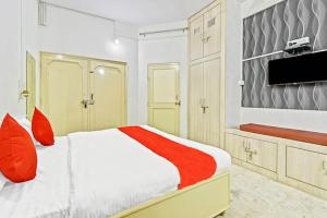 Abode Homestay في جايبور: غرفة نوم بسرير ومخدات حمراء وتلفزيون