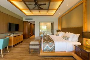 a hotel room with a bed and a television at The Gantari Ubud Hotel & Villa in Ubud