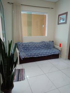 a bed in a room with a window and a plant at Praia com Conforto in Guaratuba