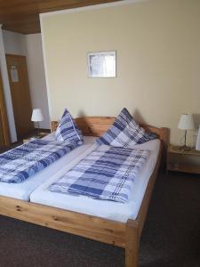 2 Betten in einem Zimmer mit blauen und weißen Kissen in der Unterkunft Gasthaus zur Krone in Feilbingert