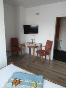 a living room with a table and chairs and a tv at Gasthaus zur Krone in Feilbingert