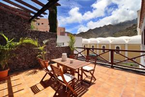 eine Terrasse mit einem Holztisch und Stühlen auf dem Balkon in der Unterkunft Hotel Escuela Rural Casa Los Herrera in Hermigua