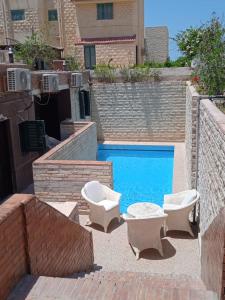 a swimming pool with two lounge chairs and a swimming pool at no 4and5 Basement Chalets 2 Beds Green Beach on the pool 114b in El Alamein