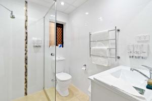 a white bathroom with a toilet and a shower at Quality Hotel Robertson Gardens in Brisbane