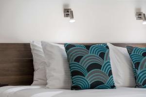 a bed with white pillows and blue and green patterns at Quality Hotel Robertson Gardens in Brisbane