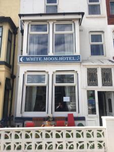 a white moon hotel with red chairs in front of it at White Moon Hotel in Blackpool