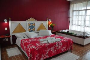 a red bedroom with a large bed with a red blanket at Pousada e Spa Vrindávana in Teresópolis