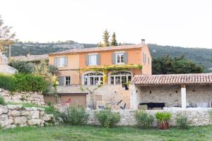 een groot huis met een stenen muur bij Le Mas Silvestre in Saint-Saturnin-dʼApt