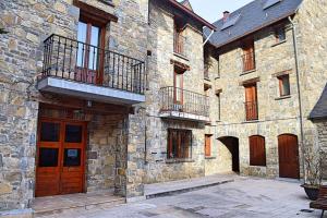 ein großes Steingebäude mit Holztüren und einem Balkon in der Unterkunft Telera ❅ Personalidad y matices nórdicos ❀❀ in Sallent de Gállego