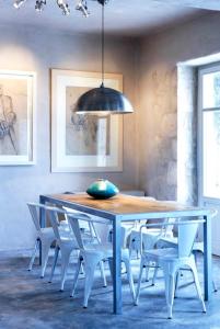 a dining room table with white chairs and a black light fixture at To Throni in Tselendáta