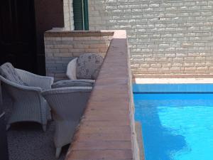 patio z 2 krzesłami przy basenie w obiekcie 2B equipped basement chalet with 2 beds pool view green beach villa 114b w mieście El Alamein