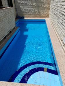 a swimming pool with blue water and a brick wall at 2B equipped basement chalet with 2 beds pool view green beach villa 114b in El Alamein
