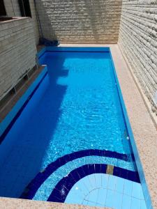エル・アラメインにある2B equipped basement chalet with 2 beds pool view green beach villa 114bの青い水とレンガの壁のスイミングプール