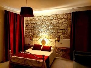 Papiroom's في سيراكوزا: غرفة نوم بجدار حجري وسرير بمخدات حمراء