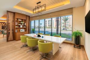 Holiday Inn & Suites Al Jubail, an IHG Hotel في الجبيل: غرفة طعام مع طاولة بيضاء وكراسي خضراء