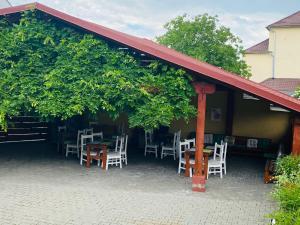 patio z białymi krzesłami, stołami i drzewami w obiekcie Pensiunea Central w mieście Reghin
