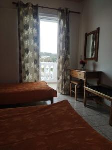 Schlafzimmer mit einem Fenster, einem Schreibtisch und einem Fenster mit Aussicht in der Unterkunft Angelina Studios in Kardamaina