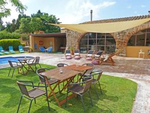 eine Terrasse mit einem Tisch, Stühlen und einem Pool in der Unterkunft Masia Ca La Caputxeta & Golf in Castelló d'Empúries