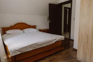 een slaapkamer met een bed met witte lakens en een spiegel bij Vila Alsace Podu' cu Lanturi in Bacău