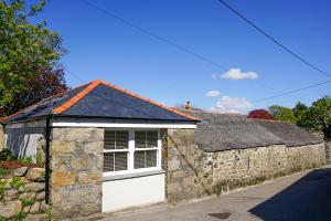 um edifício de pedra com uma porta de garagem branca em The Annex, Tregoddick Barn em Penzance