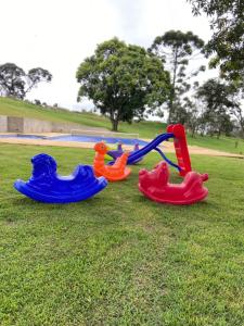 three childrens play equipment on the grass in a park at CHÁCARA VENEZA in São Roque