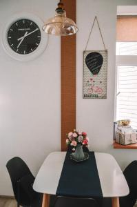 a dining room table with a clock and a vase of flowers at LUCKY 7 apartment in Liepāja
