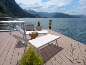 eine Holzterrasse mit einem Tisch und Stühlen auf dem Wasser in der Unterkunft Belvilla by OYO Belvedere 2 in Marone