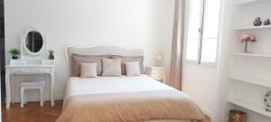 a white bedroom with a white bed and a mirror at Villa Angelus in Nice