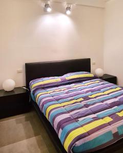 um quarto com uma cama com um edredão listrado colorido em 27Apartment em Ancona