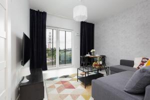 Una sala de estar con un sofá y una ventana. en Business Center Apartments Warsaw Wola by Noclegi Renters, en Varsovia