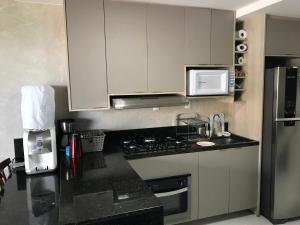 a kitchen with white cabinets and a black counter top at MAUÍ BEACH RESIDENCE - Beira-mar Tamandaré- Próximo a Igreja de São Pedro- PE in Tamandaré