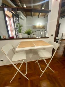 una mesa con sillas blancas en una habitación en Cathedral Sweet home en Palermo