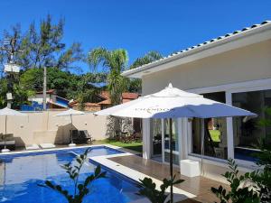 a swimming pool with an umbrella next to a house at Parador Búzios Boutique Hotel in Búzios
