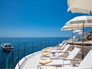 un grupo de sillas y sombrillas en un barco en el agua en Palazzo Avino en Ravello